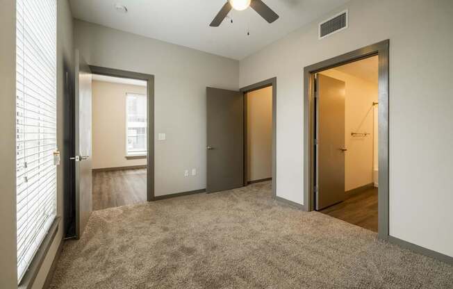 Carpeted bedroom with ceiling fan, closet, and bathroom