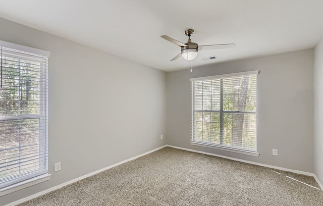 A room with a ceiling fan and carpeted floor.