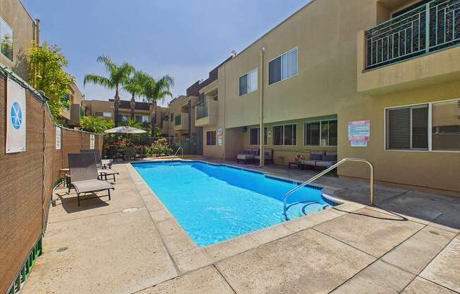 A small pool surrounded by a concrete patio and a building.