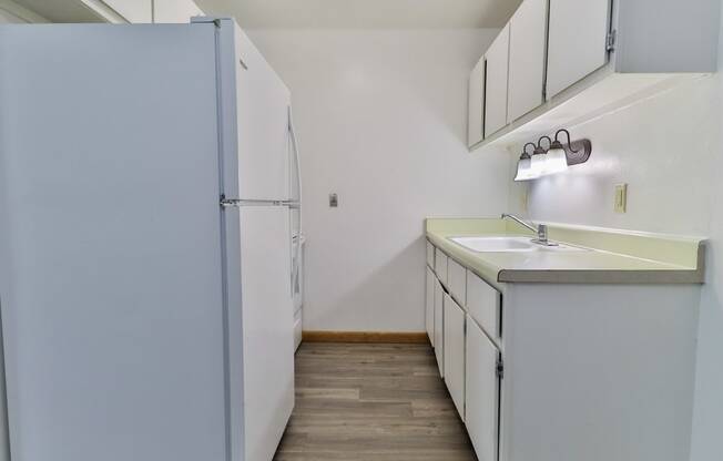 an empty kitchen with a refrigerator and a sink