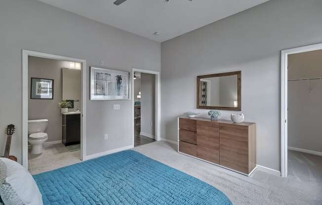a bedroom with a blue bed and a bathroom with a toilet at Nexus at Sandhill, Columbia
