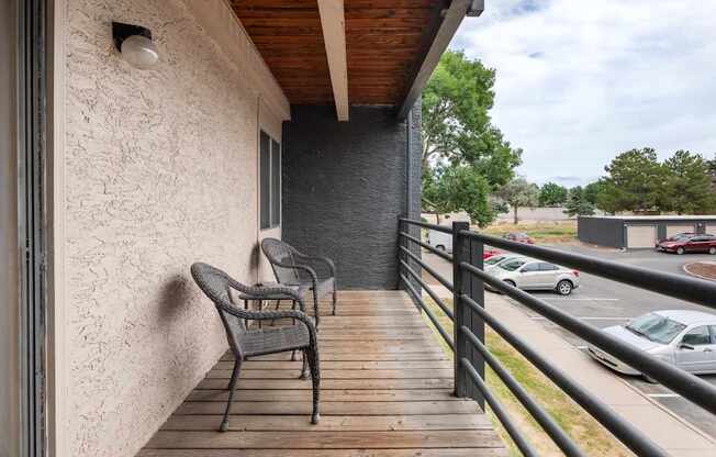 a balcony with two chairs and a building with a parking lot