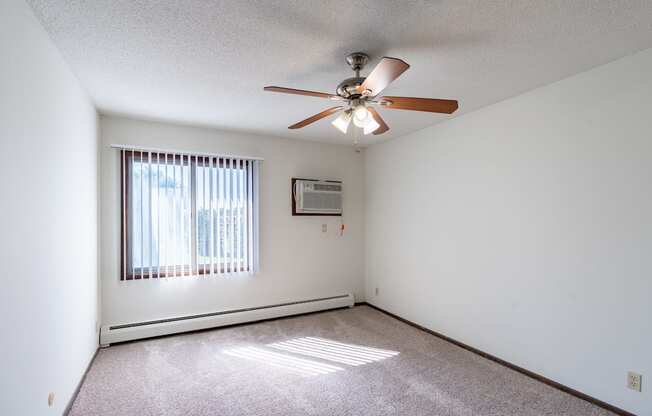 a bedroom with a ceiling fan and a window. Eagan, MN Glen Pond Apartments
