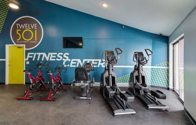 a gym with cardio equipment and a fitness center sign on the wall