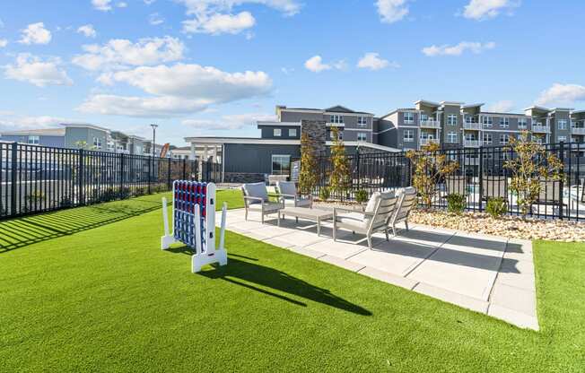 a yard with benches and chairs and a fence with apartments in the background