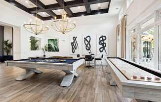 A pool table is in the middle of a room with a wooden floor and a black ceiling.