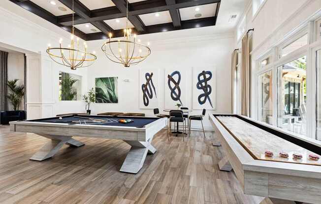 A pool table is in the middle of a room with a wooden floor and a black ceiling.