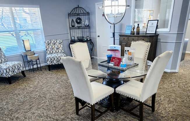Clubhouse lounge at Skyler Ridge featuring a glass coffee table and white accent chairs with natural lighting.