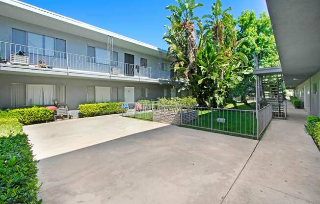 the courtyard of an apartment building with a patio and a fence