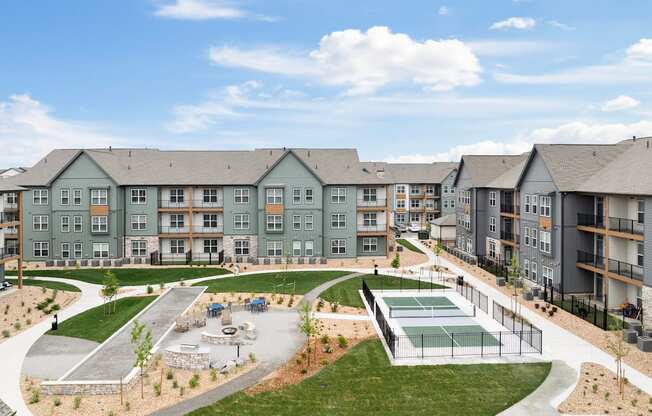 an exterior view of an apartment complex with a tennis court and a pool