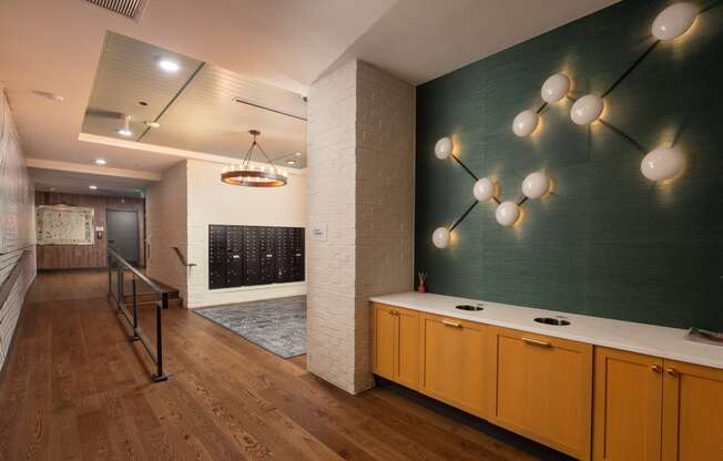 Spacious walkway to the mail area with chic wall decorations on the green wall and modern style chandelier at Sylvan Uptown, Colorado