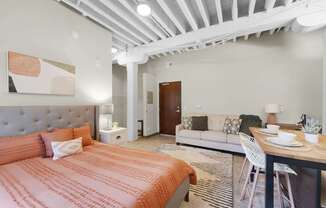 A bedroom with a bed, a couch, and a dining table.