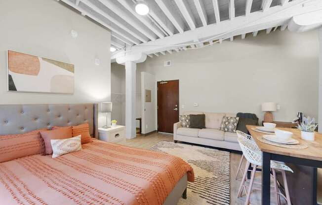 A bedroom with a bed, a couch, and a dining table.