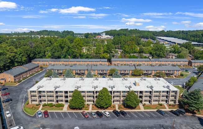 an aerial view of a large building with a parking lot and trees