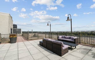 A patio with a couch, table, and lamp posts.