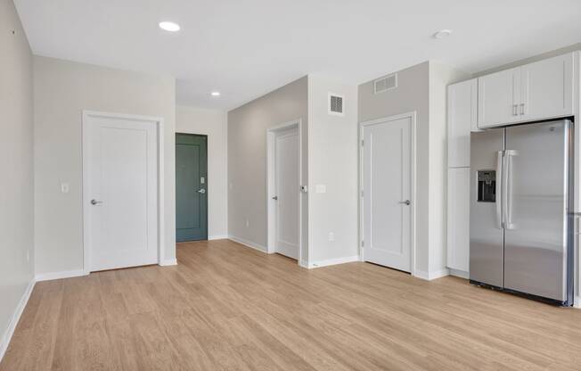 a bedroom with a medium sized bed and a refrigerator in a room with a hardwood floor
