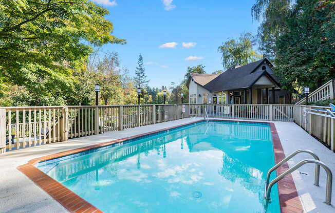 A small pool surrounded by a fence and trees.