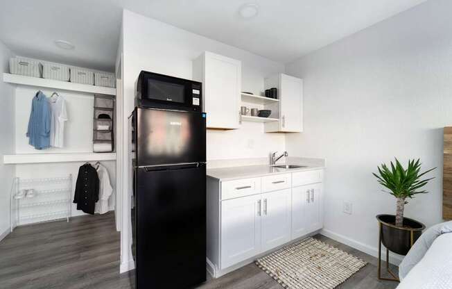 A black fridge in a kitchen with white cabinets and a white wall.