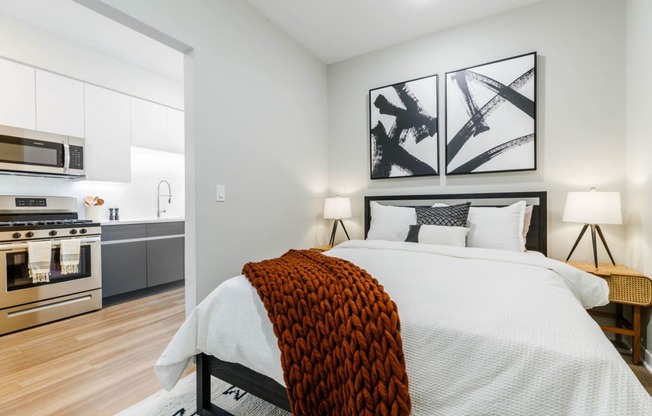 a bedroom with a large bed and a kitchen at One Ten Apartments, Jersey City