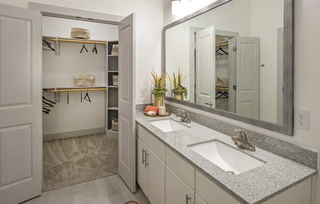 a bathroom with two sinks and a mirror and a closet