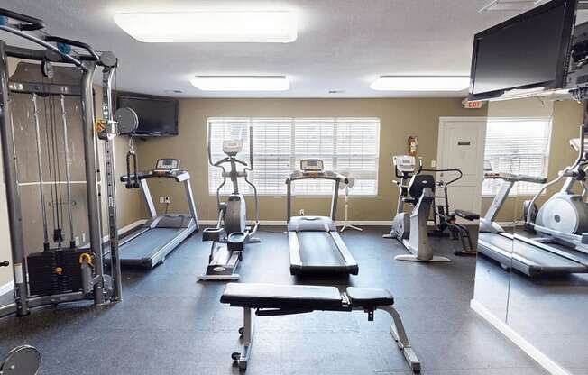 A gym with a variety of equipment including treadmills, weights, and exercise machines.