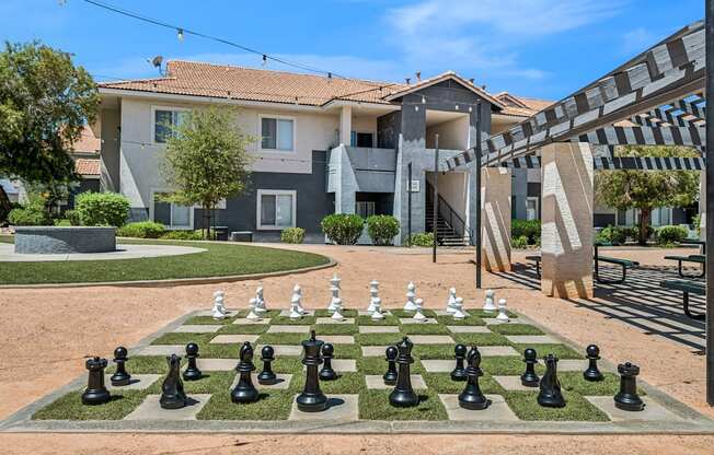 A chess board with black and white pieces in front of a building.