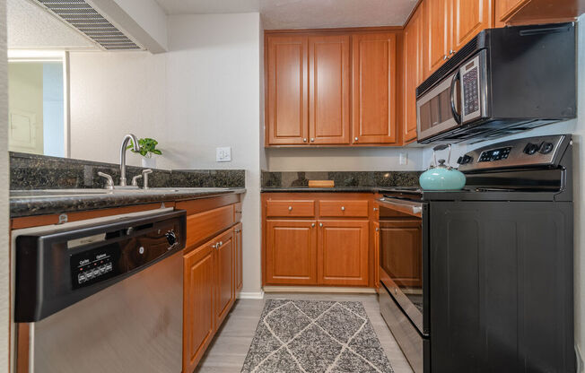 a kitchen with stainless steel appliances and wooden cabinets at City View Apartments at Warner Center, Woodland Hills California