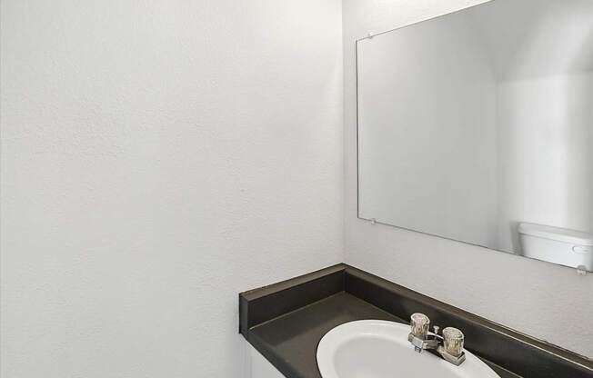 A bathroom sink with a mirror above it. at Oakstone Apartments, Clearfield, 84015
