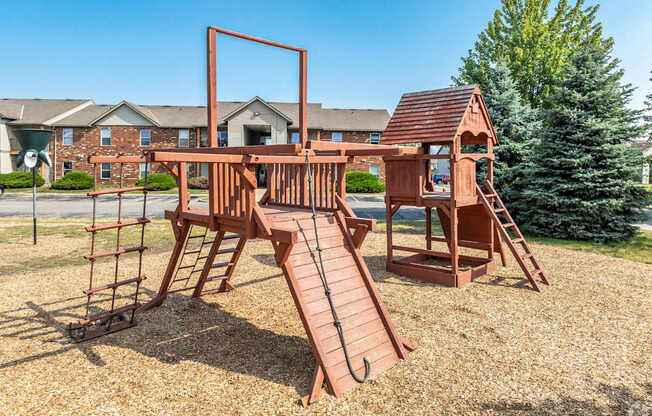 A wooden playground structure with a slide and a swing set.