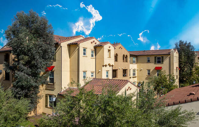 a view of a group of apartment buildings with trees in front of them
