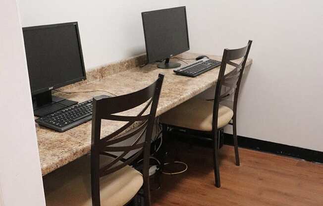 a desk with two computers and two chairs in a room