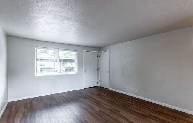 the living room of an empty house with wood flooring and a window