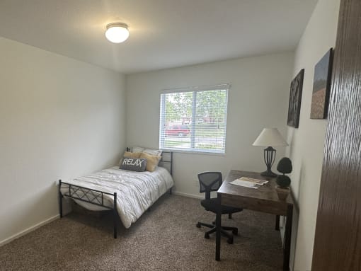 a bedroom with a bed and a desk and a window