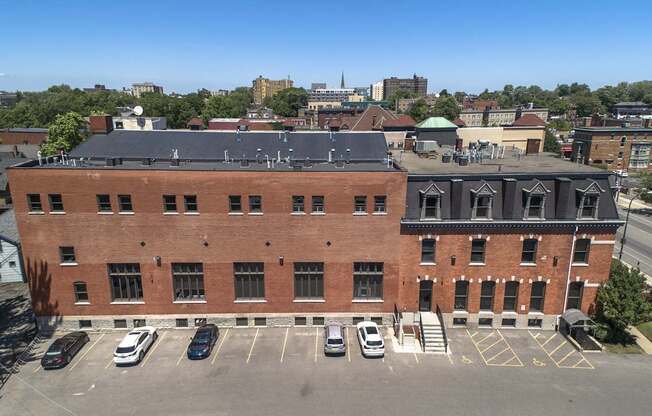 an aerial view of a brick building with cars parked in front of it at The Knights @ 506 Delaware Apartments, Buffalo, 14202