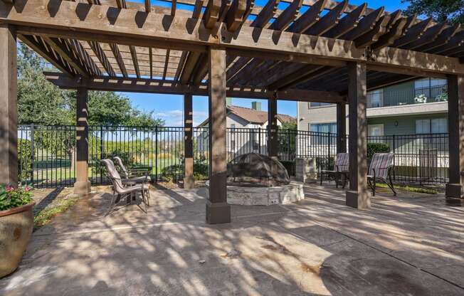 a patio with a fire pit and a pergola