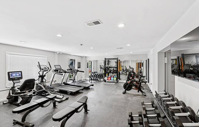 A spacious gym with a variety of equipment including treadmills, elliptical machines, and weight machines.