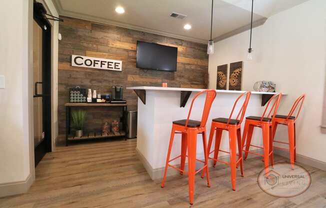 a bar with four orange stools in front of a coffee shop with a fireplace