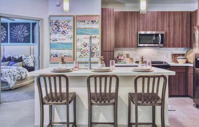 A kitchen with a table set for two and a fridge to the right.