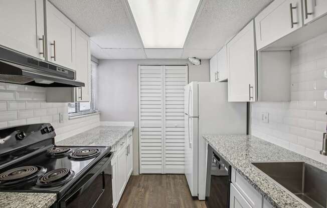 A kitchen with a black stove top oven and white cabinets.