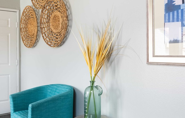 a living room with a blue chair and a vase