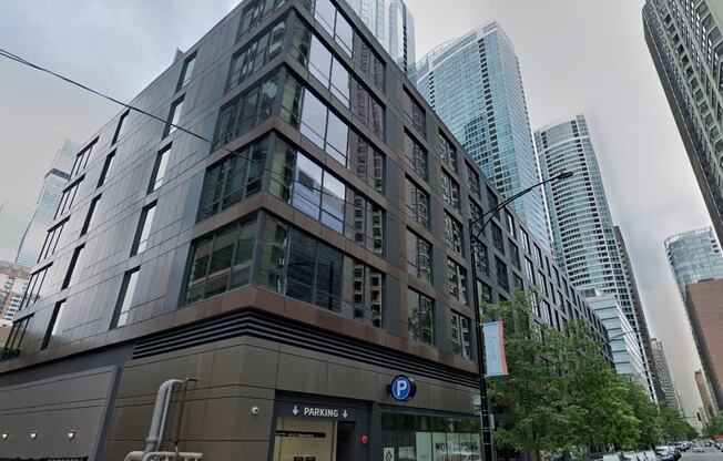 a building on the corner of a city street with skyscrapers