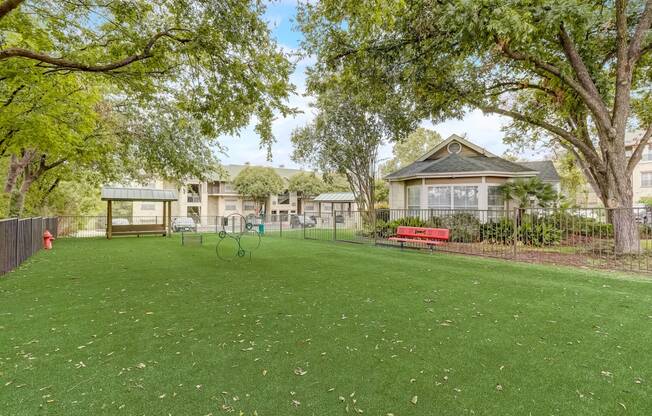 a park with a red bench in front of a house
