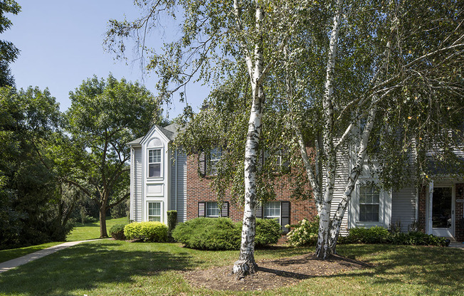 Exterior of Westridge Gardens with tall tress, freshly cut grass, and a walking path