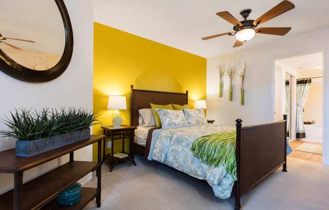 a bedroom with a yellow accent wall and a ceiling fan