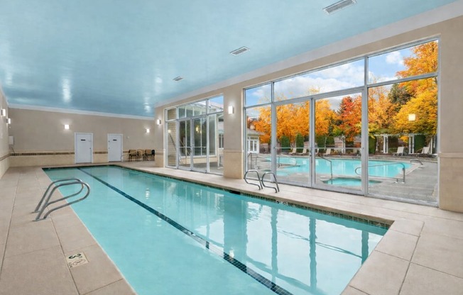 A large indoor swimming pool with a view of the outdoors through the windows.