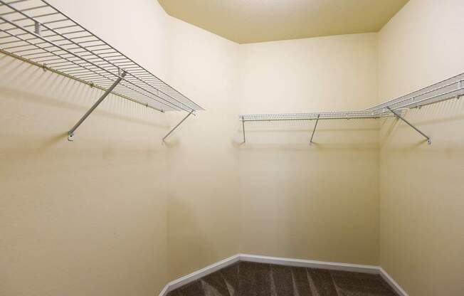 A walk-in closet with a metal rack and a carpeted floor.