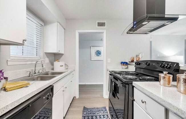 a kitchen with white cabinets and a black stove and a sink