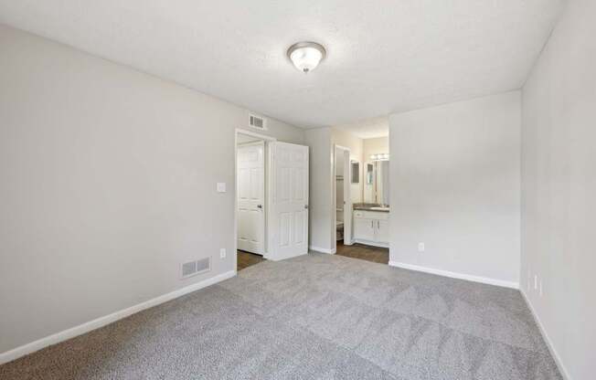 A bedroom with carpet leading to a bathroom and closet  at Gwinnett Square Apartments in Duluth, GA