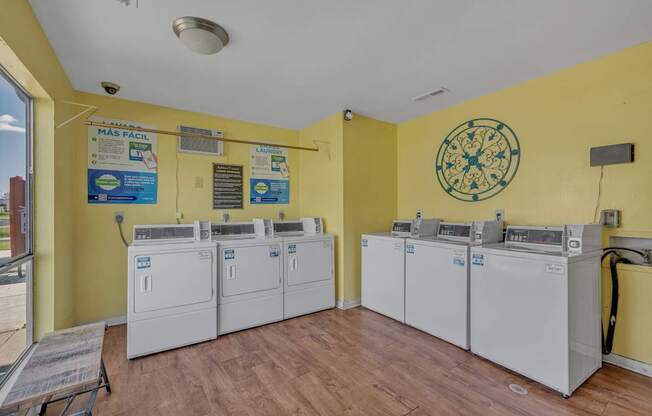 A yellow wall with a clock and washing machines.