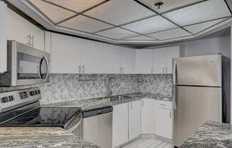 A kitchen with white cabinets and a granite counter top.
